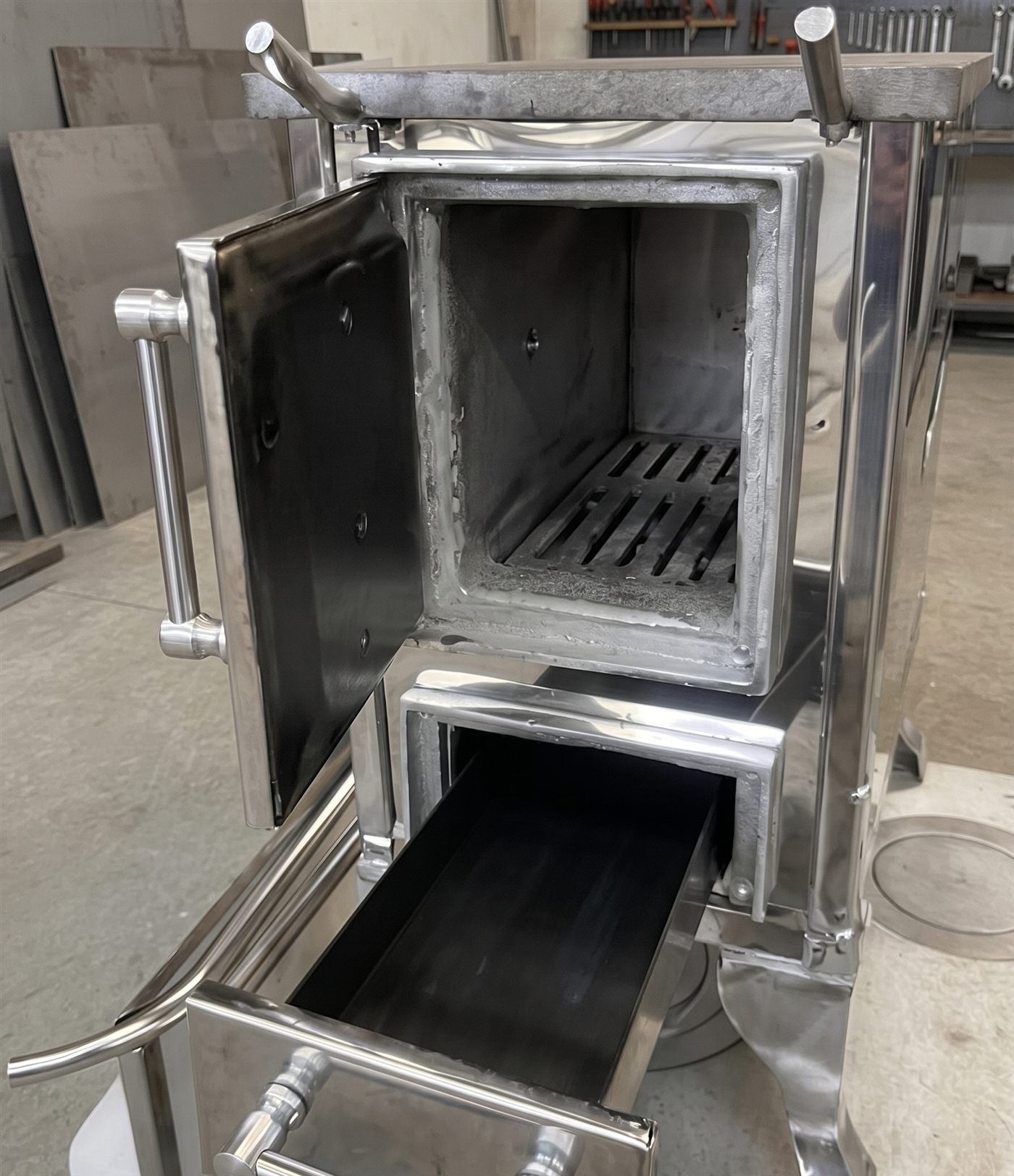 Cocina a leña de acero inoxidable con horno y cajón cenicero abiertos
