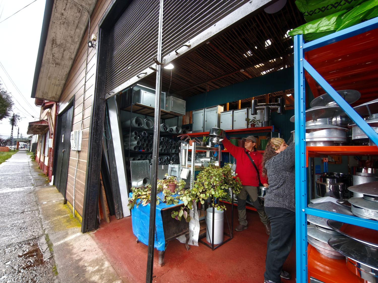 Atención a una clienta en la entrada del local, bajando una pieza de la estantería