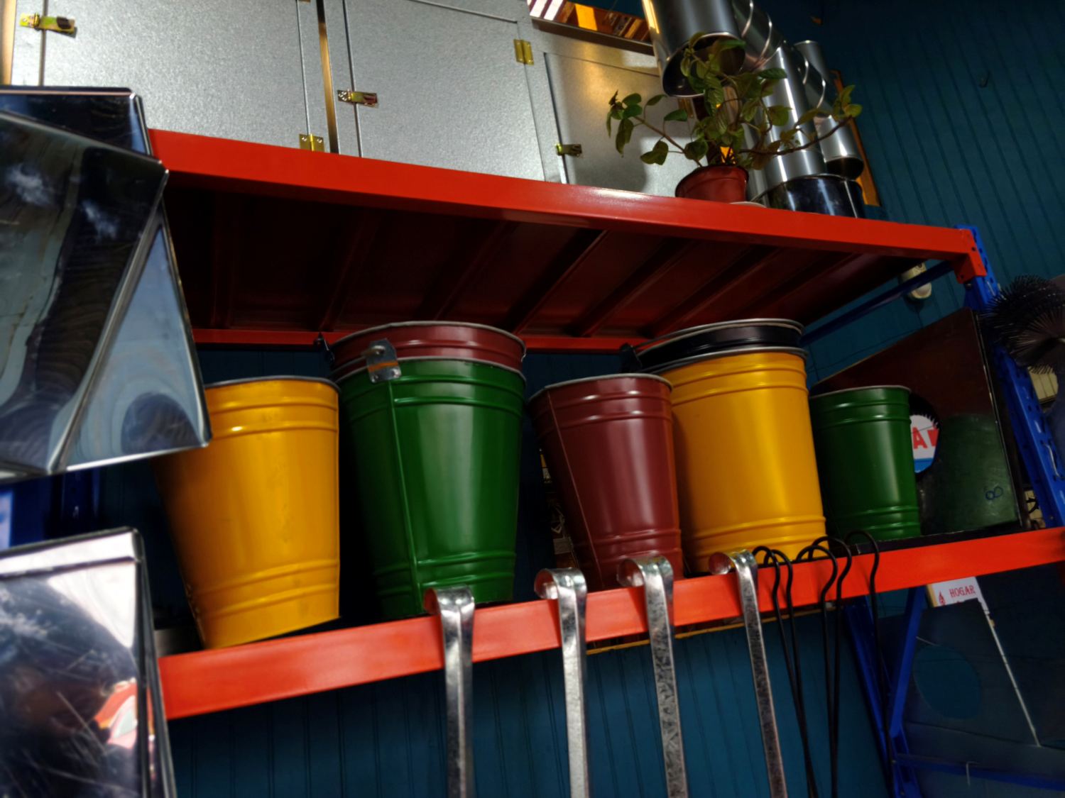 Tambores metálicos pintados en amarillo, verde y rojo, en la estantería del local