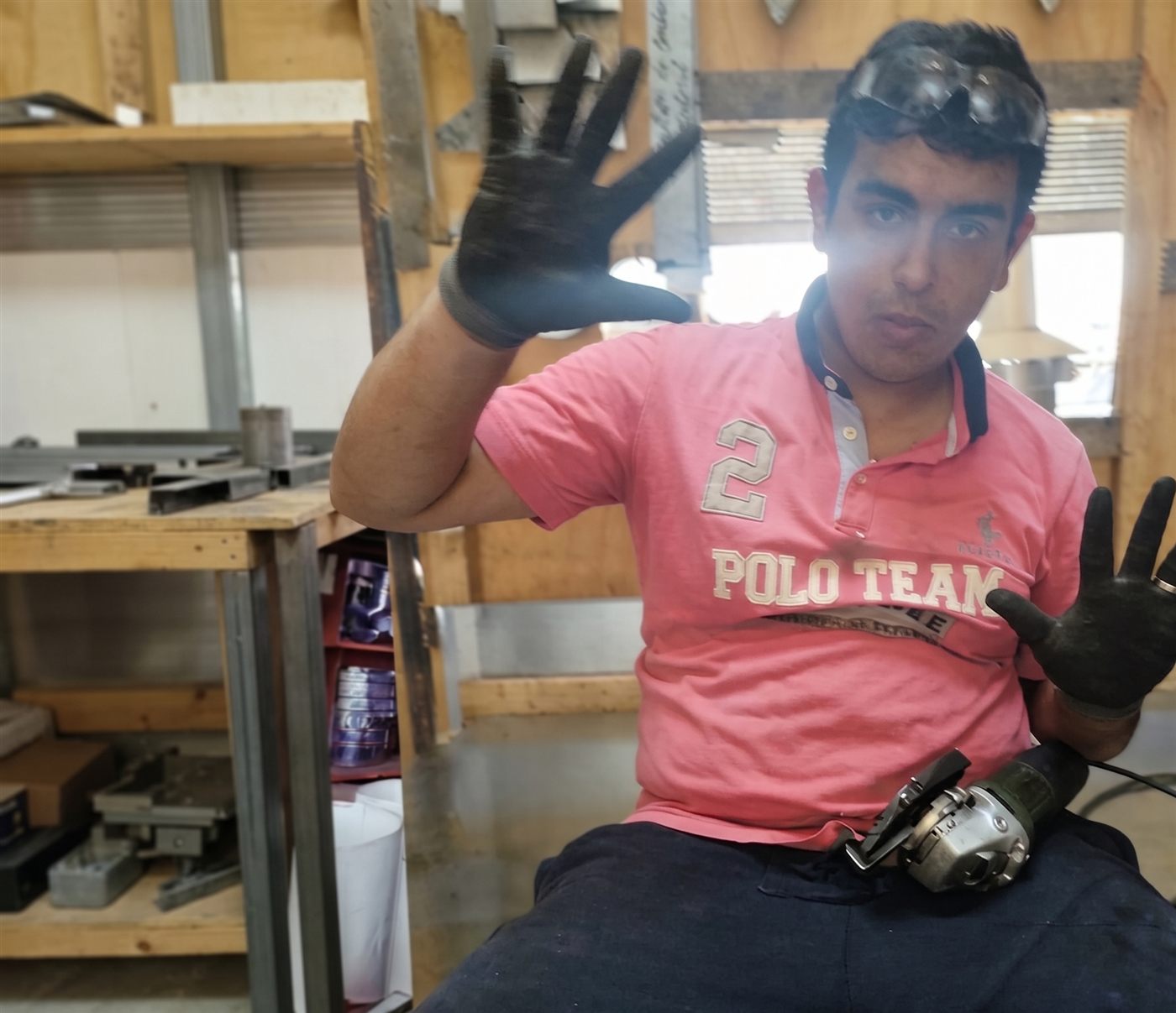 El hijo de Miguel trabajando en el taller con guantes y herramienta eléctrica